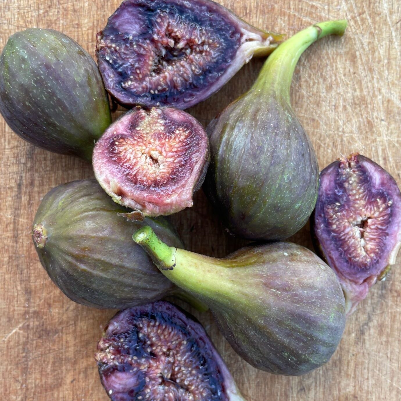 A selection of ripe Brown Turkey Figs on wooden chopping board.