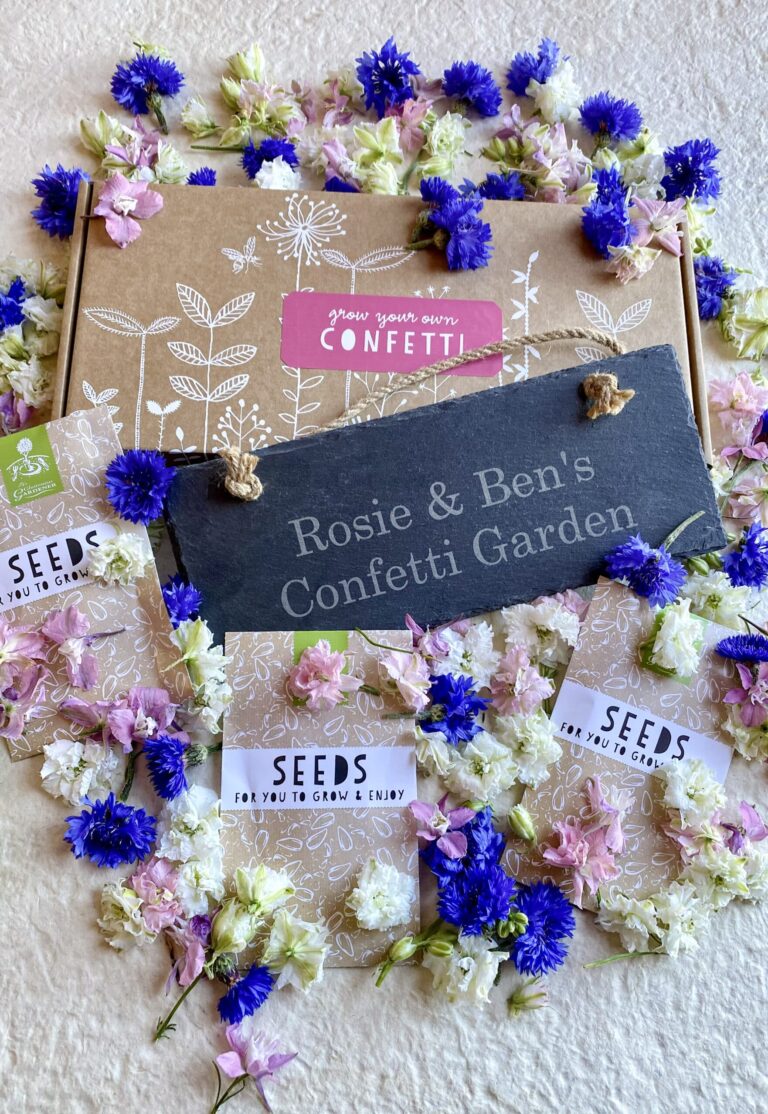 Confetti seed box with personalised slate and seed packets against white background and vibrant flowers.