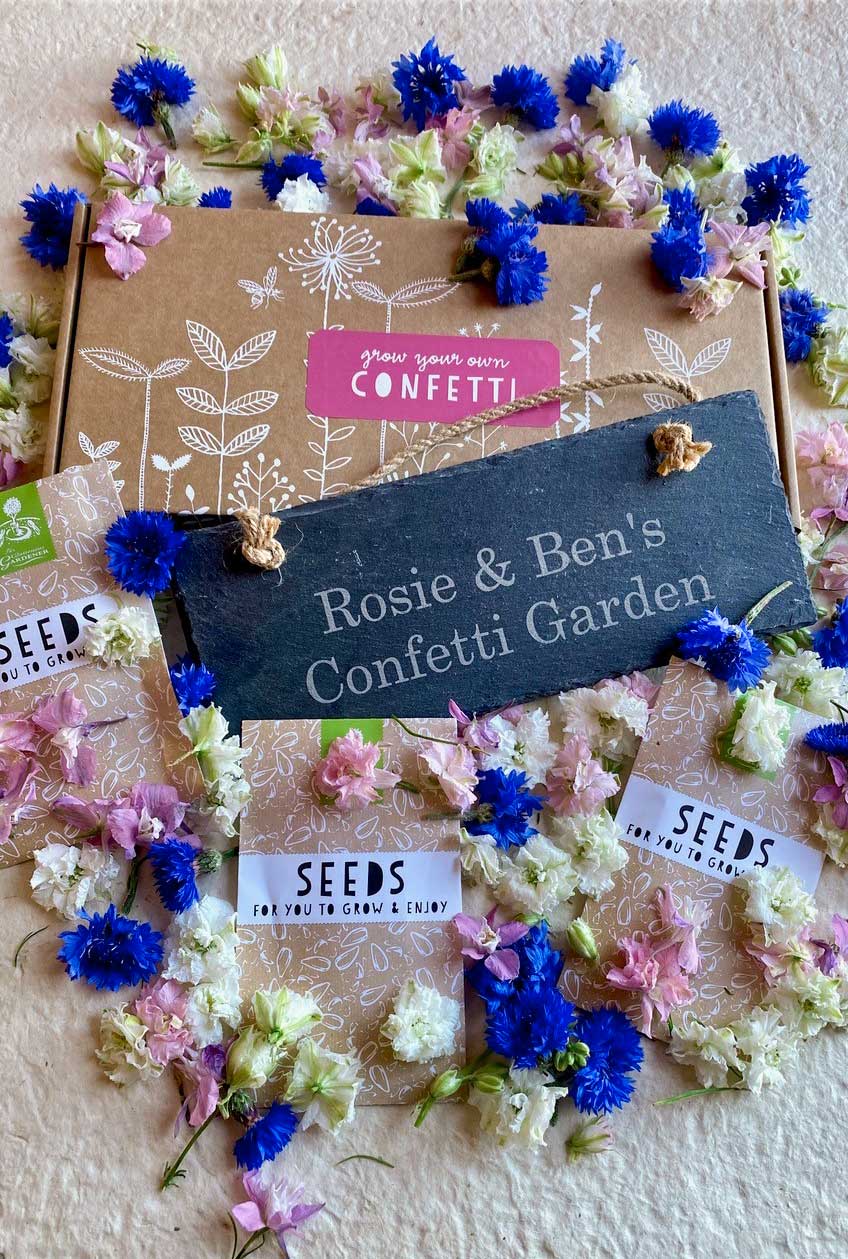 Confetti seed box with personalised slate and seed packets against white background and vibrant flowers.