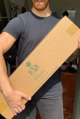 A large cardboard transportation box for a gift crate held by a man.