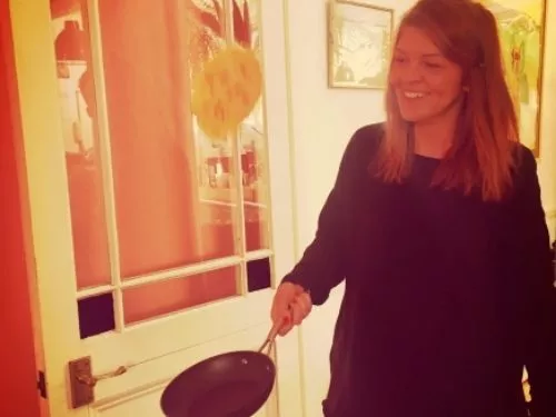 A woman holding a pan in front of a glass door.