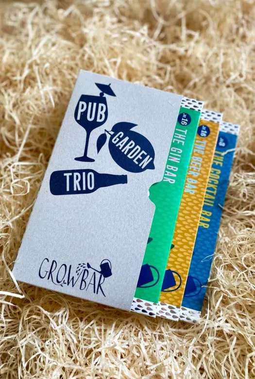 A grey pub garden trio box containing three different growbars in blue. beige and green colour, nestled in wood wool.