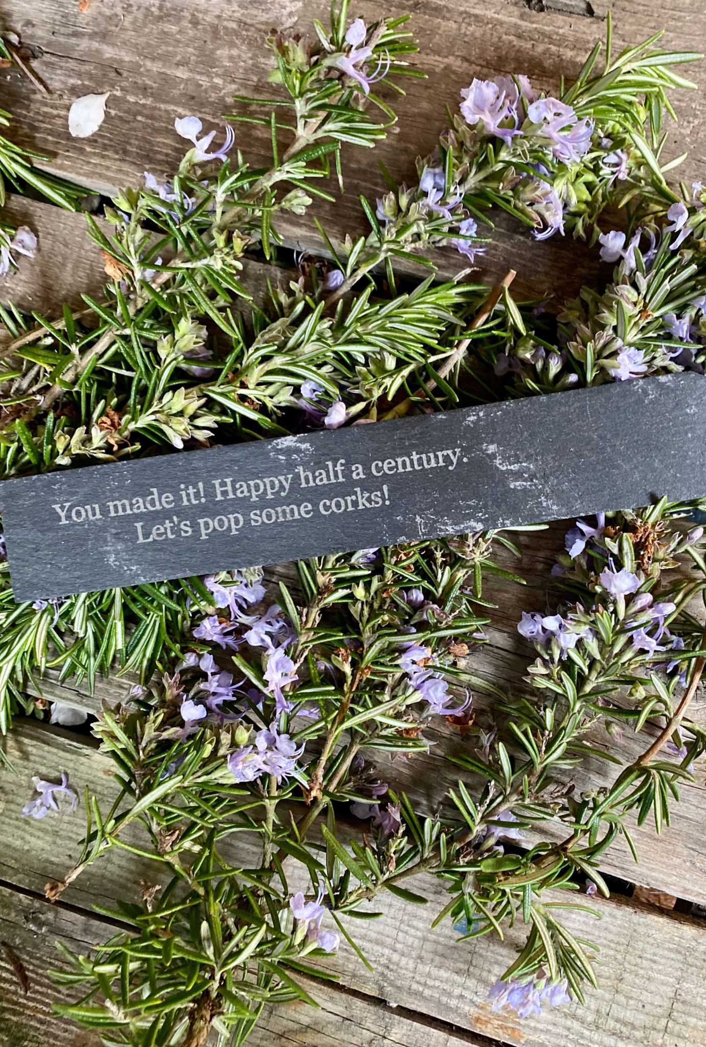 Personalised slate label amongst purple flowering plants.