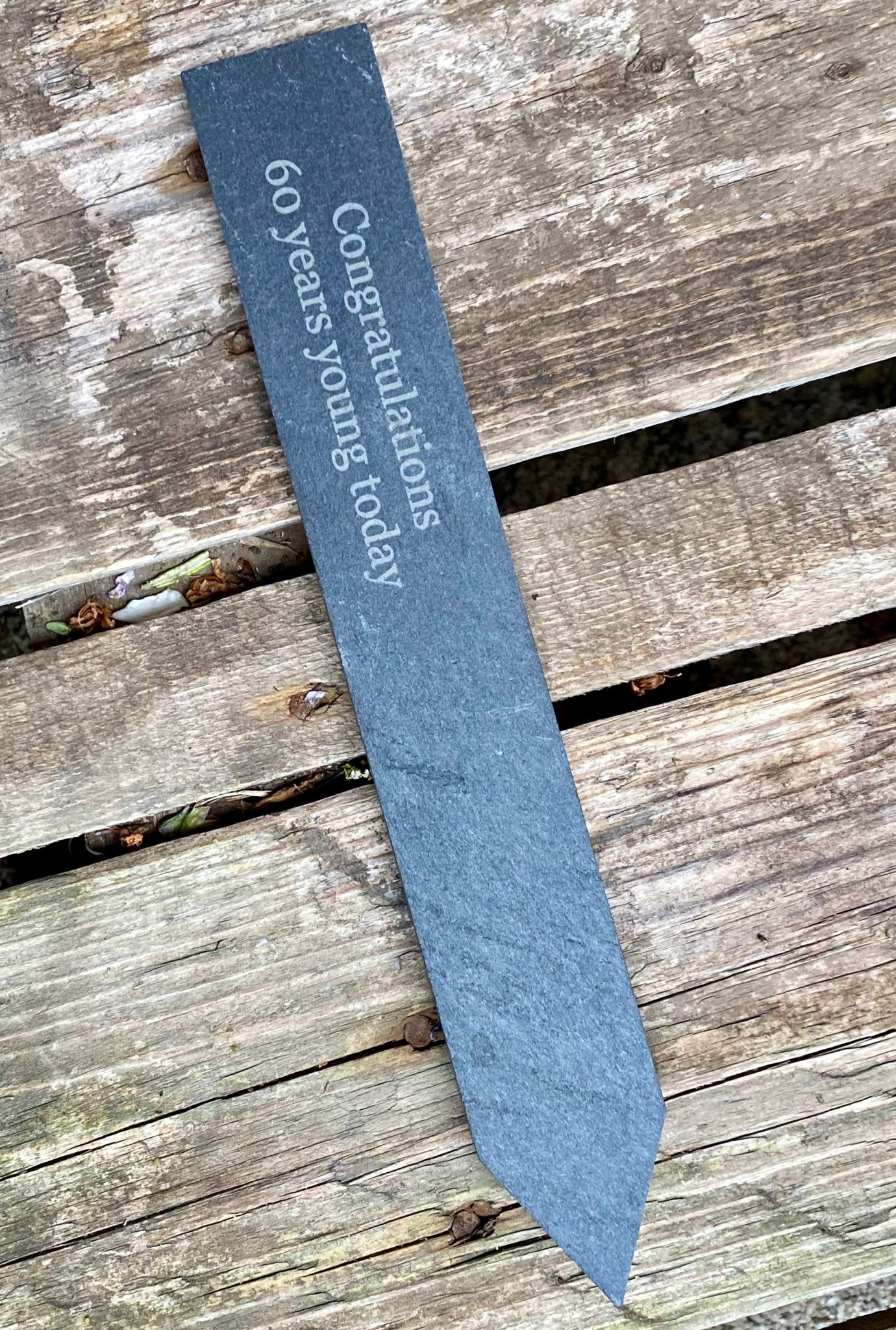 Personalised slate label shown on wooden decking.