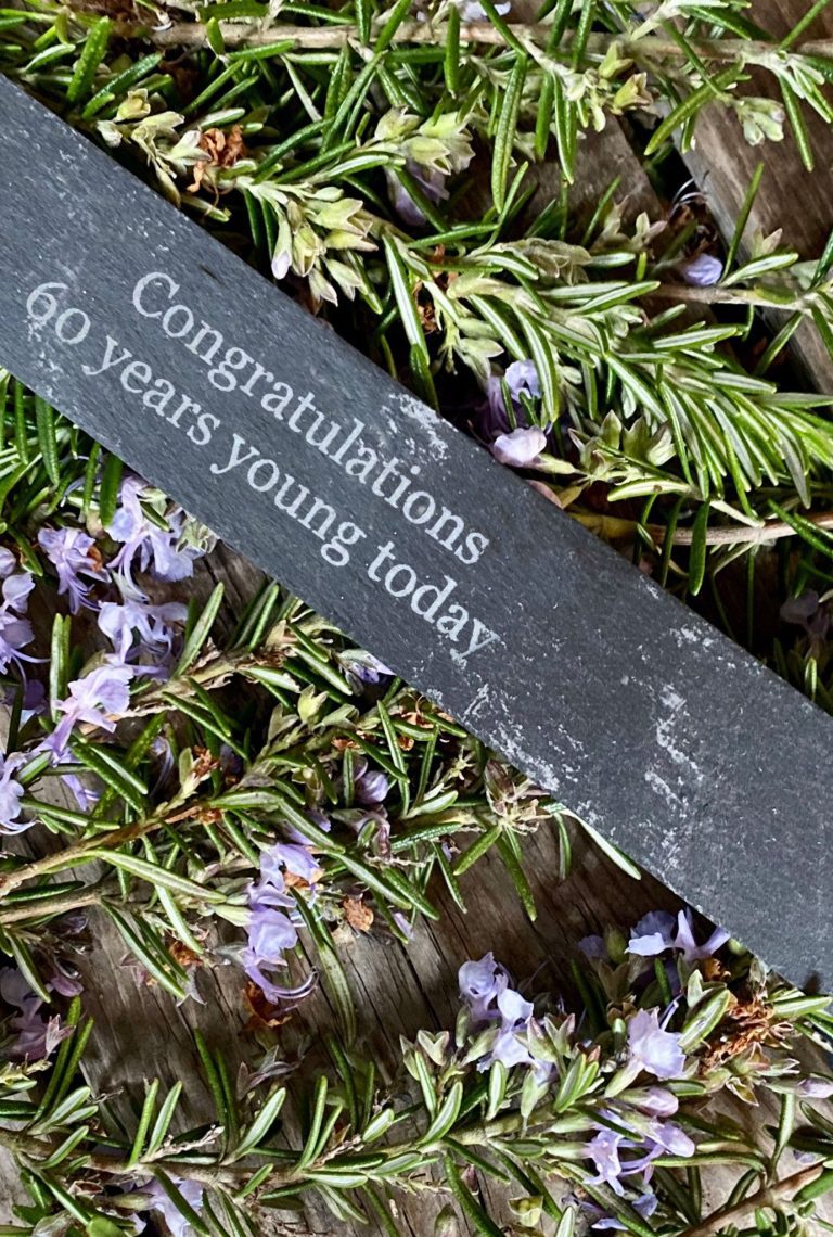 Personalised slate label amongst purple flowering plants.