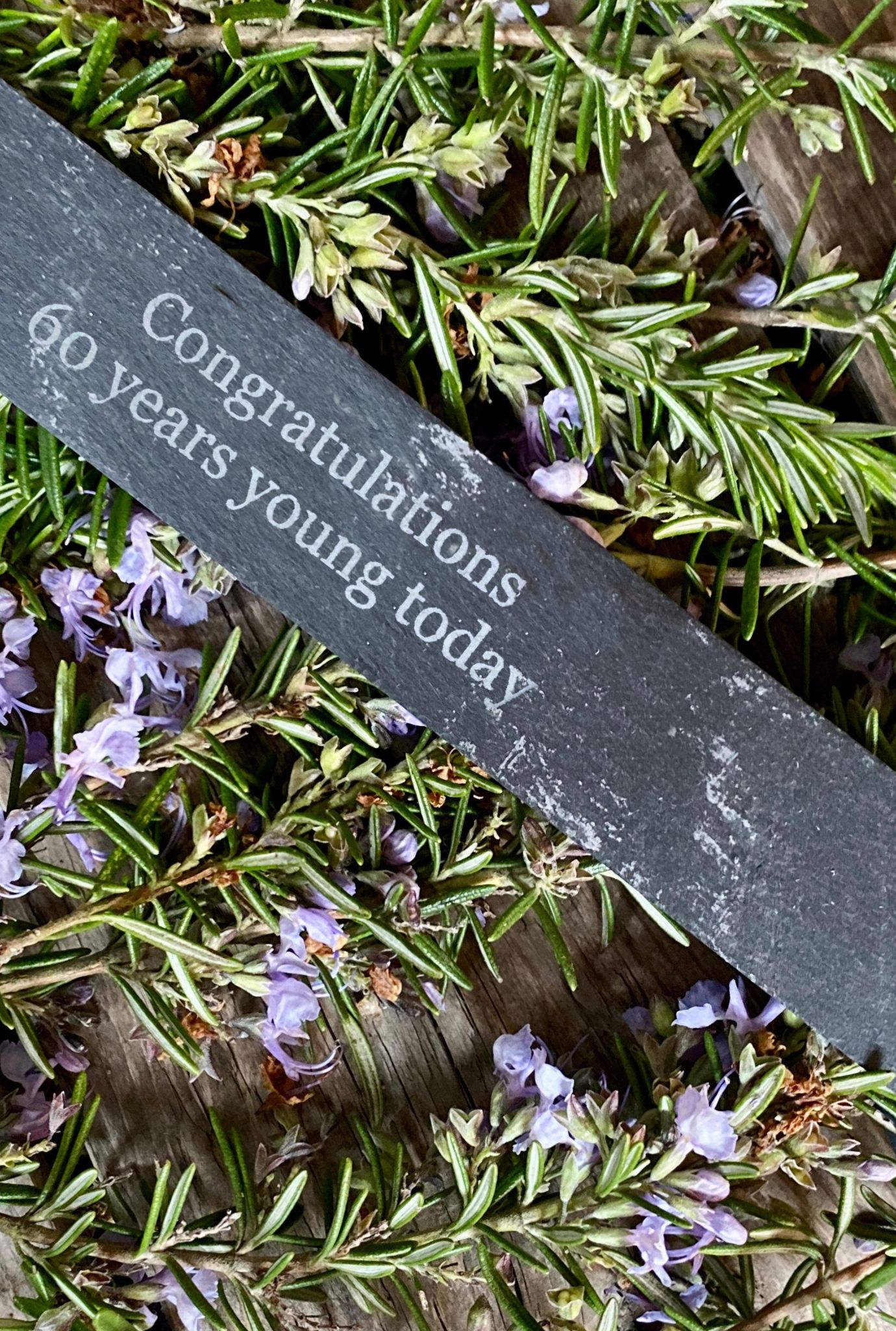 Personalised slate label amongst purple flowering plants.