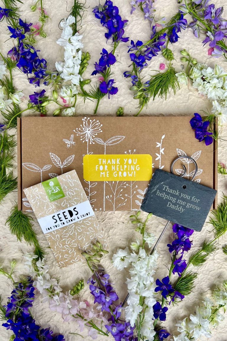 Thank You seed box with personalised slate and seed packets against white background and vibrant flowers.