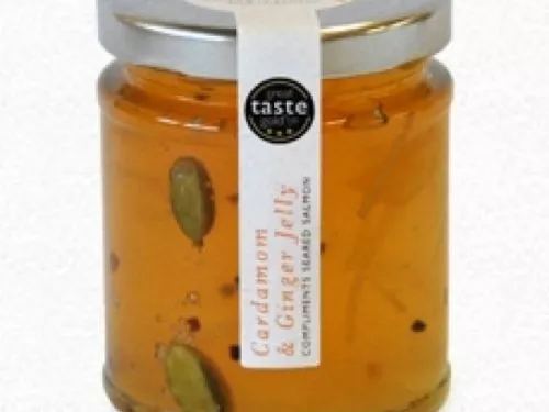 A glass jar with an amber coloured Cardamom Ginger Jelly cardamom seeds and a silver lid.