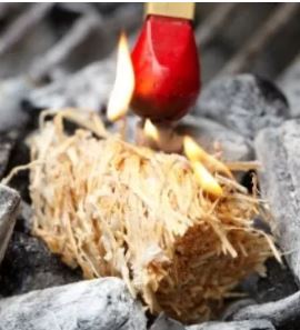 Close up of wood wool fire lighter being lit by red match.