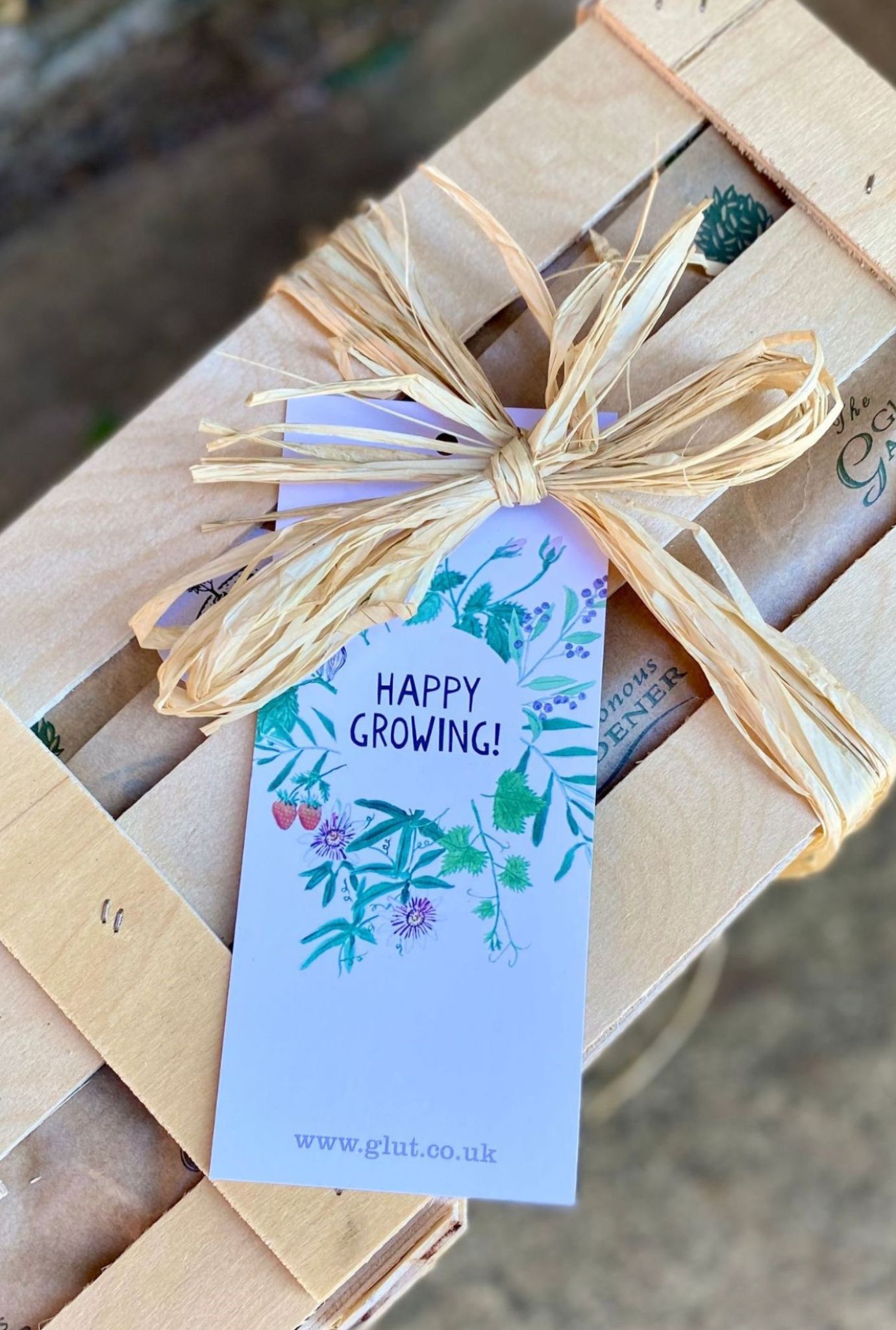 Close up of a Happy Growing gift label attached to a wooden crate with twine.