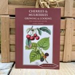 Close up of maroon-coloured Cherries & Mulberries Growing & Cooking book in front of two wooden crates.